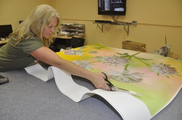 Production Manager Annie Scheuring cuts off excess canvas from a digital thermal print before hand-stretching it over a frame. MICHELLE TRAURING