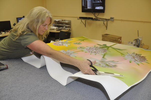 Production Manager Annie Scheuring cuts off excess canvas from a digital thermal print before hand-stretching it over a frame. MICHELLE TRAURING