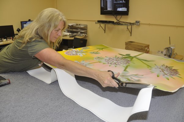 Production Manager Annie Scheuring cuts off excess canvas from a digital thermal print before hand-stretching it over a frame. MICHELLE TRAURING