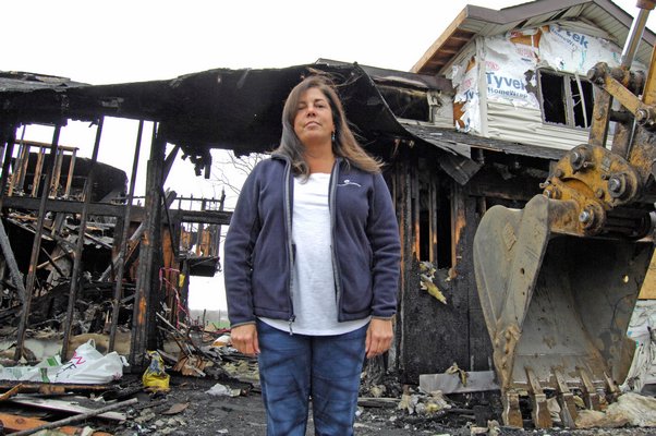 Theresa Kiernan stands before her home, which was destroyed by fire on March 3. The structure is set to be demolished on Monday.   DANA SHAW