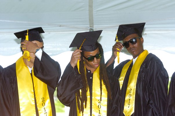 Kevin Feliciano, Ameer El and Nykell Dean move their tassels after graduating.