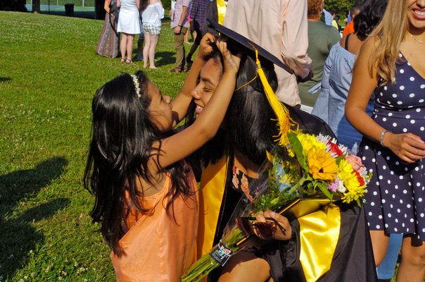 Graduate Sarahi Negrete gets a hand with her cap from Dayza Lopez.
