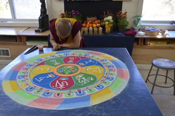 Lama Tenzin works on the mandala, drawing designs into the sand. SHAYE WEAVER