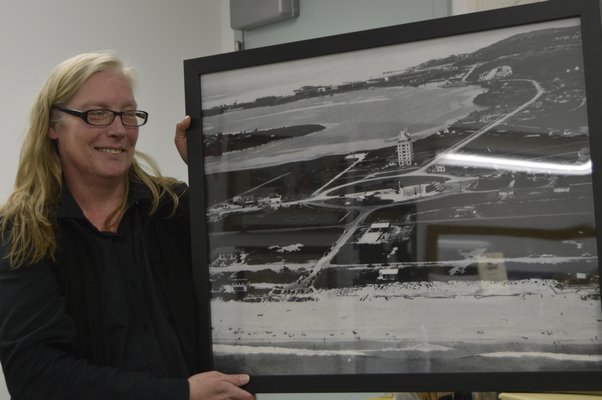 Robin Strong with one of the framed prints of historic Montauk photos in the book and library exhibit. VIRGINIA GARRISON