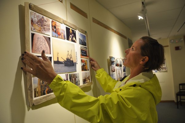 Wendi Blair rehangs one of the collages in her exhibit, "A Tribute to All Fishermen." MICHELLE TRAURING