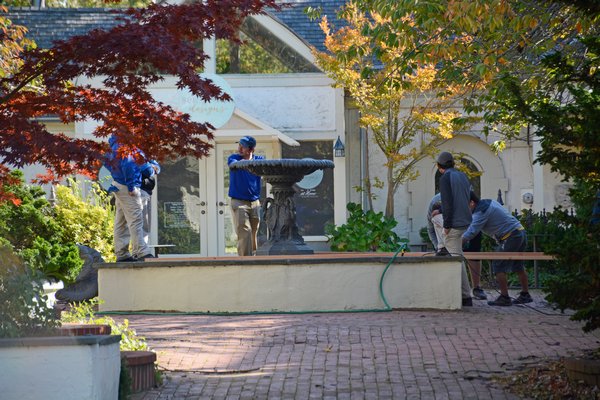 Workers drain and remove a fountain from a retail courtyard on Jobs Lane in October. JD ALLEN