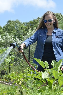 Stephanie Turano waters her plot at a community garden she helped create in Eastport. BY ERIN MCKINLEY
