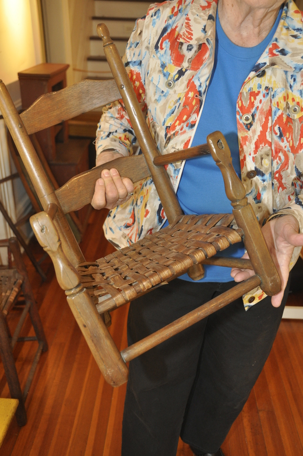 Gerri MacWhinnie shows the wear and tear on the front of an antique chair, caused by a child tilting it over and using it as a walking assistant. MICHELLE TRAURING