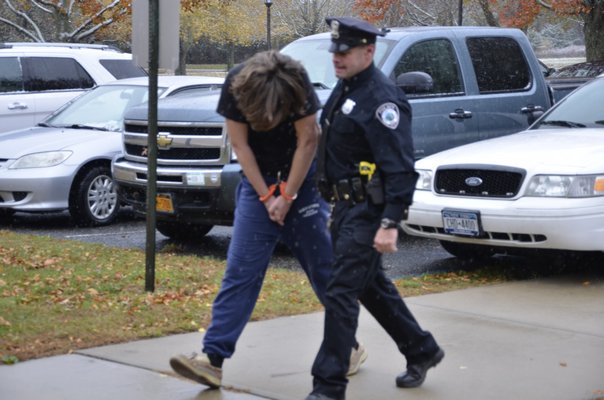 John X. Tracy III is brought in to justice court by an East Hampton Town Police officer on Tuesday.