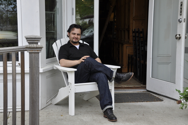 Black Swan Antiques owner Randy Kolhoff sits on the porch of his Bridgehampton store in a Seaside Casual Adirondack chair.