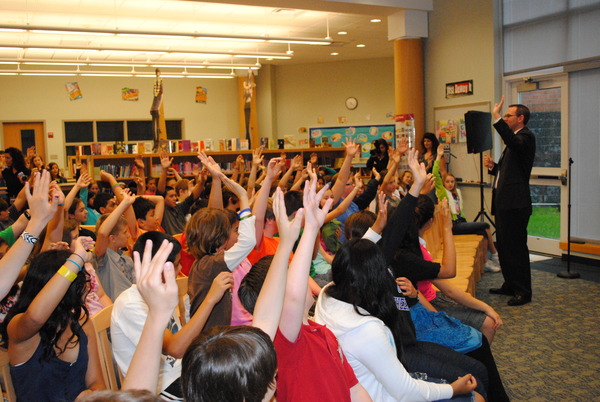 Lars Clemensen, superintendent of Hampton Bays Public Schools, far right, asking 120 children who gathered in the library at Hampton Bays Middle School Friday, June 17, how many of them made pins for the Haiti Houses project.