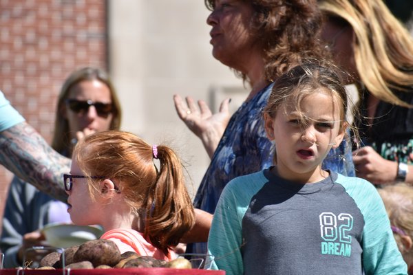 Third-grader Abigail Law, right, fills bags with produce from her school's farm at Saturday's famer's market. CHRIS PERAINO