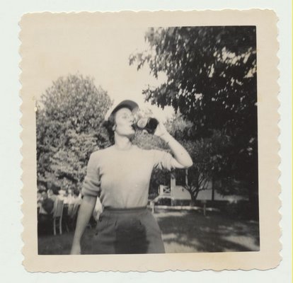 A woman takes a refreshing swig of her drink. NORTH SEA BEACH COLONY