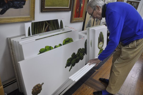 Henry Koehler flips through his artichoke paintings in his Southampton studio. BY MICHELLE TRAURING