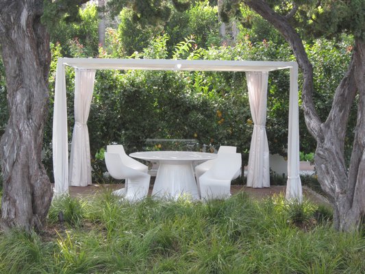 White outdoor furniture under a white-curtained white pergola. MARSHAL WATSON