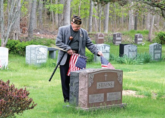 May 22: Brian Carabine places a flag on a grave at Most Holy Trinity Cemetery in East Hampton.