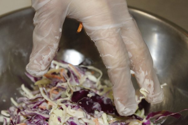 Arielle Ferrara mixes the cabbage with Hamptons Farms special sauce to create their signature coleslaw side. VALERIE GORDON