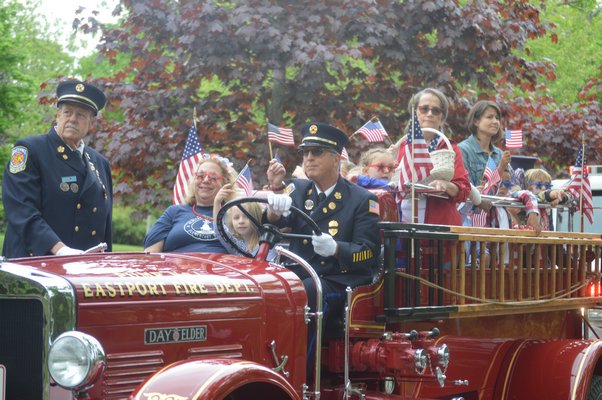 As part of tradition, kindergartener Amelia DiMartino and her teacher, Debbie Johnson, ride in the Eastport Fire Department's antique fire truck during Friday's Remsenburg-Speonk Elementary School Memorial Day Parade. Also pictured are Eastport firefighters Tom Collins and Randy Crennan, right. JENNIFER BIGORA