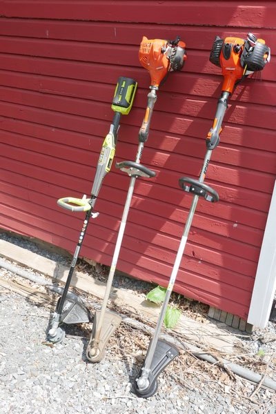 Three very different string trimmers. On the left is the battery powered Ryobi, which claims to have “gas-like power." In the middle is the consumer-level Echo model SRM 225, and on the right is the commercial-level Echo 266T. They are about 11, 12 and 14 pounds respectively. ANDREW MESSINGER