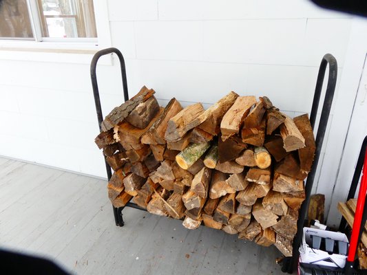 Simple metal wood racks can store several days of firewood but, like this one, the wood should be several inches off the floor and the wood should be four to five inches from the house exterior and never touching it.  ANDREW MESSINGER