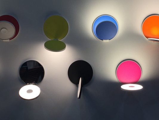 Ingenious wall-mounted discs in rainbow colors flip open, rotate and can be aimed for illumination simply by twisting them. MARSHALL WATSON