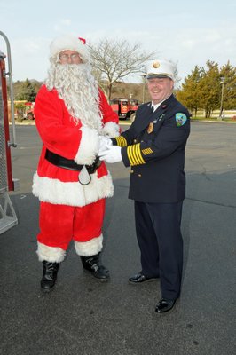 Jimmy Wright, dressed as Santa Claus, greets Fire Department Chief Joe Lenahan on Santa's visit to the Montauk Fire Department on Sunday. RICHARD LEWIN