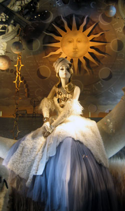 Bergdorf’s “autumn” window provides an extravaganza of celestial symbols with a voluptuously silk clad mannequin floating atop a “paper moon” decoupaged in the New York Times classified section. MARSHALL WATSON