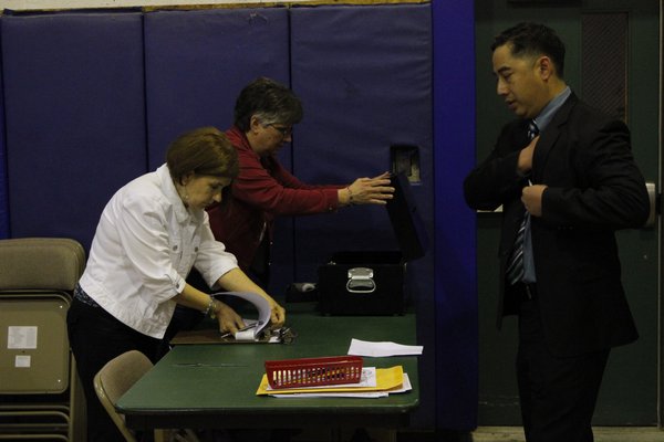 Officials from the East Quogue School District look on as the absentee ballots are tallied Tuesday night. BY CAROL MORAN
