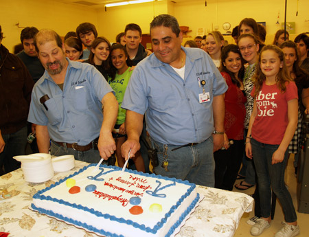 Custodians Fermey Zea and Mike Cassano cut a cake they purchased for cast and crew members of “Les Miserable