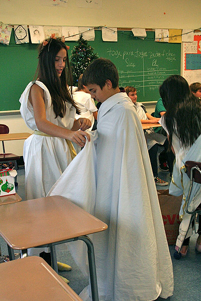 Shelby Pierson shows Matthew Giugliano how to wear his toga at the Saturnalia celebration in Southampton Intermediate School Latin class.