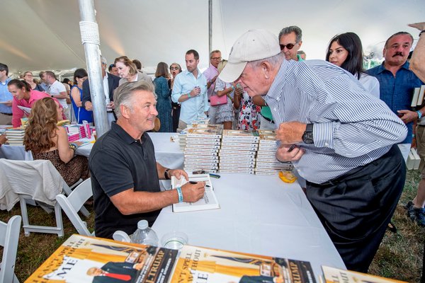 Alec Baldwin chats with a patron as he signs a copy of his book for him during the East Hampton Library's 15th Annual Authors Night Benefit under the tent at 555 Montauk Highway in Amagansett on Saturday.