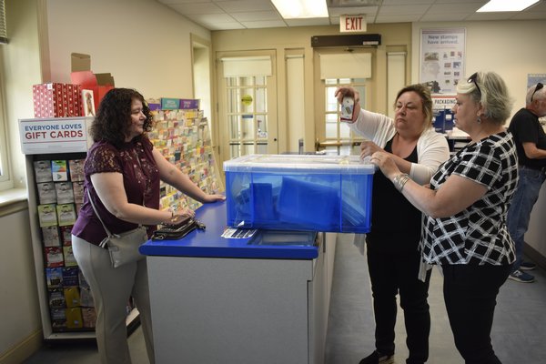 Sandra Renauro, Jacqueline Carton and Sandra Renauro use packing tape to seal shut the box of applications before transporting it to Town Hall, where it would be unsealed at noon to start the raffle.