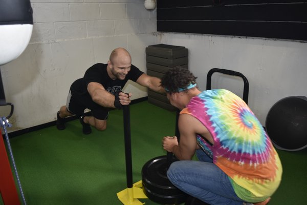 Julius Anglickas pushes friend and one of his trainers Neko Gettling on the weight sled.
