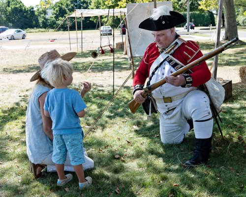 A young man is introduced to the finer points of musketry by a member of the 23rd Regiment of Foot, Royal Welch Fusiliers in America, at this weekend’s Revolutionary War encampment on the Great Lawn.