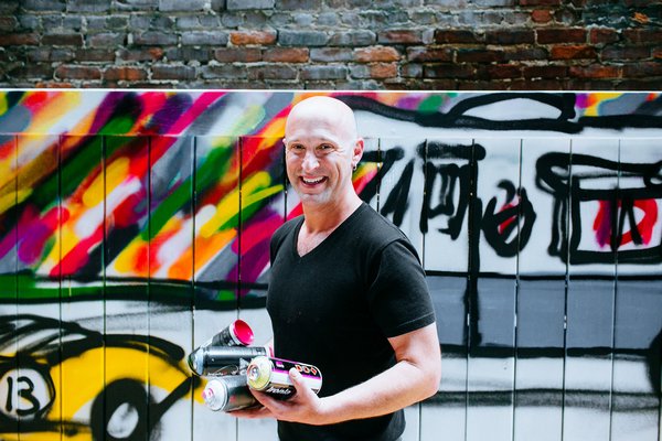 Artist Mitchell Schorr at a New York City event with one of his murals in the background.