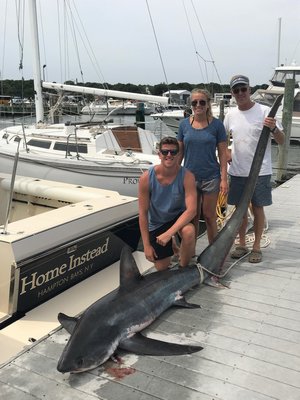 Ian Keller, Laura Zaweski and John Zaweski with a 186-pound thresher shark they caught 12 miles south of Shinnecock Inlet last week.  Courtesy of Tracy Zaweski