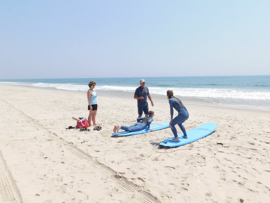 Ciaran and Phinnian O'Hare from Hershey, Pa. take a surf lesson with Lars Svanberg of Main Beach Surf & Sport Monday in Wainscott. BEN KAVA