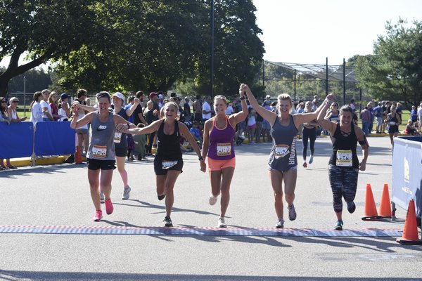 Friends cross the finish line of the half marathon hand-in-hand.