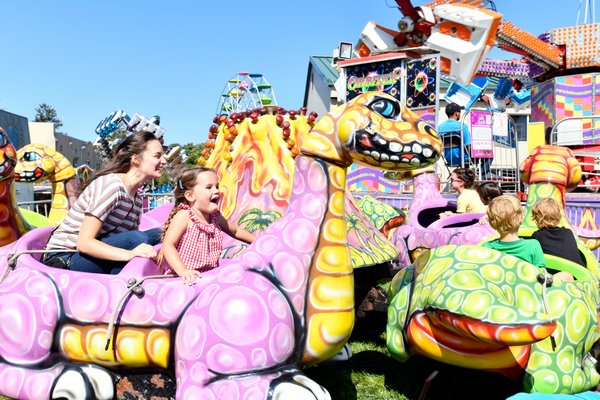 Kathleen Comber and Niama Kelly take a ride on a dinosaur at the San Gennaro Fest or the Hamptons on Saturday.