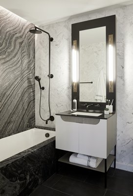An elongated custom vanity mirror in a luxurious stone bathroom. CHRISTIAN HARDER