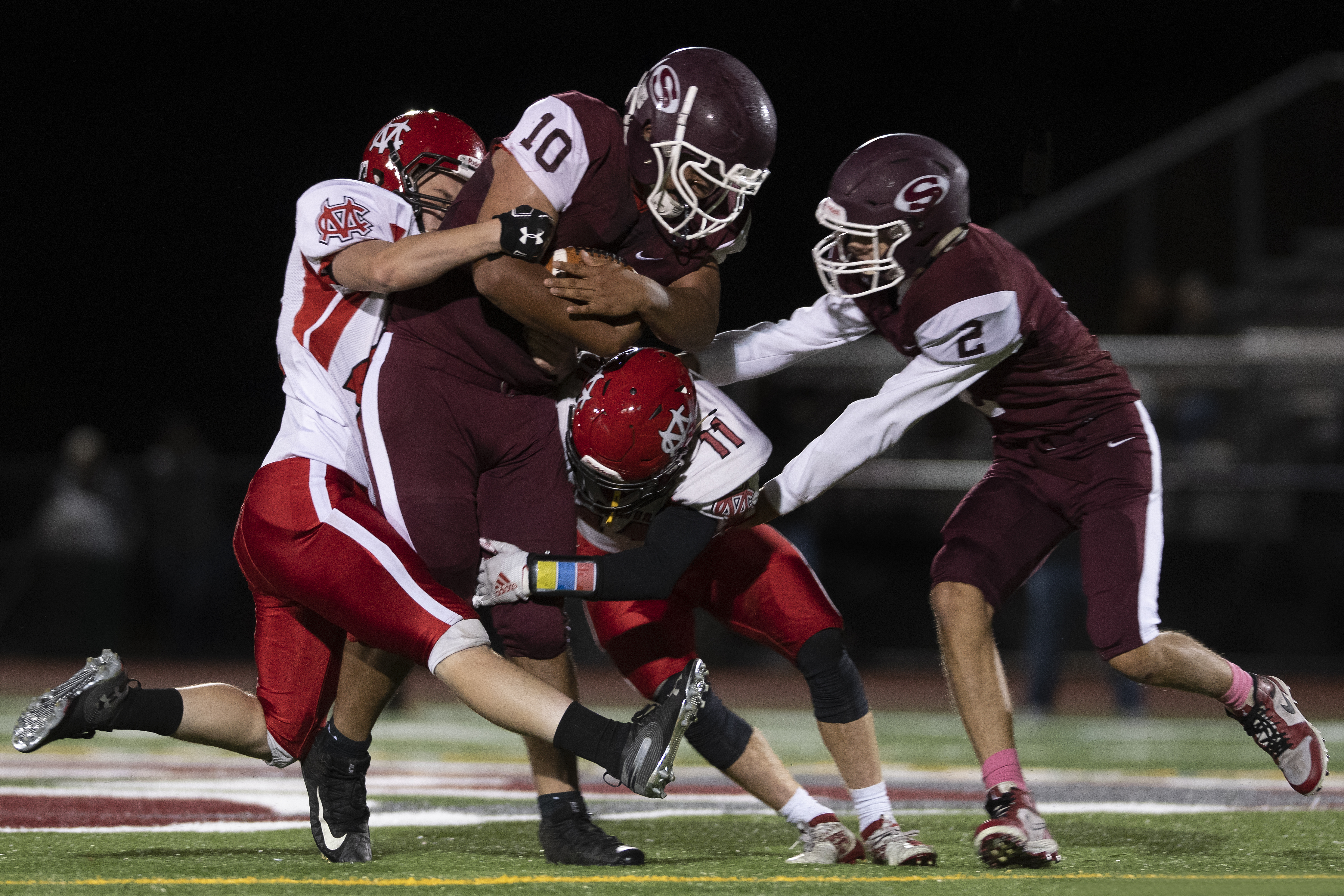 Pierson senior Dimitrius Barranco covers up the ball while being tackled by a pair of Center Moriches defenders.