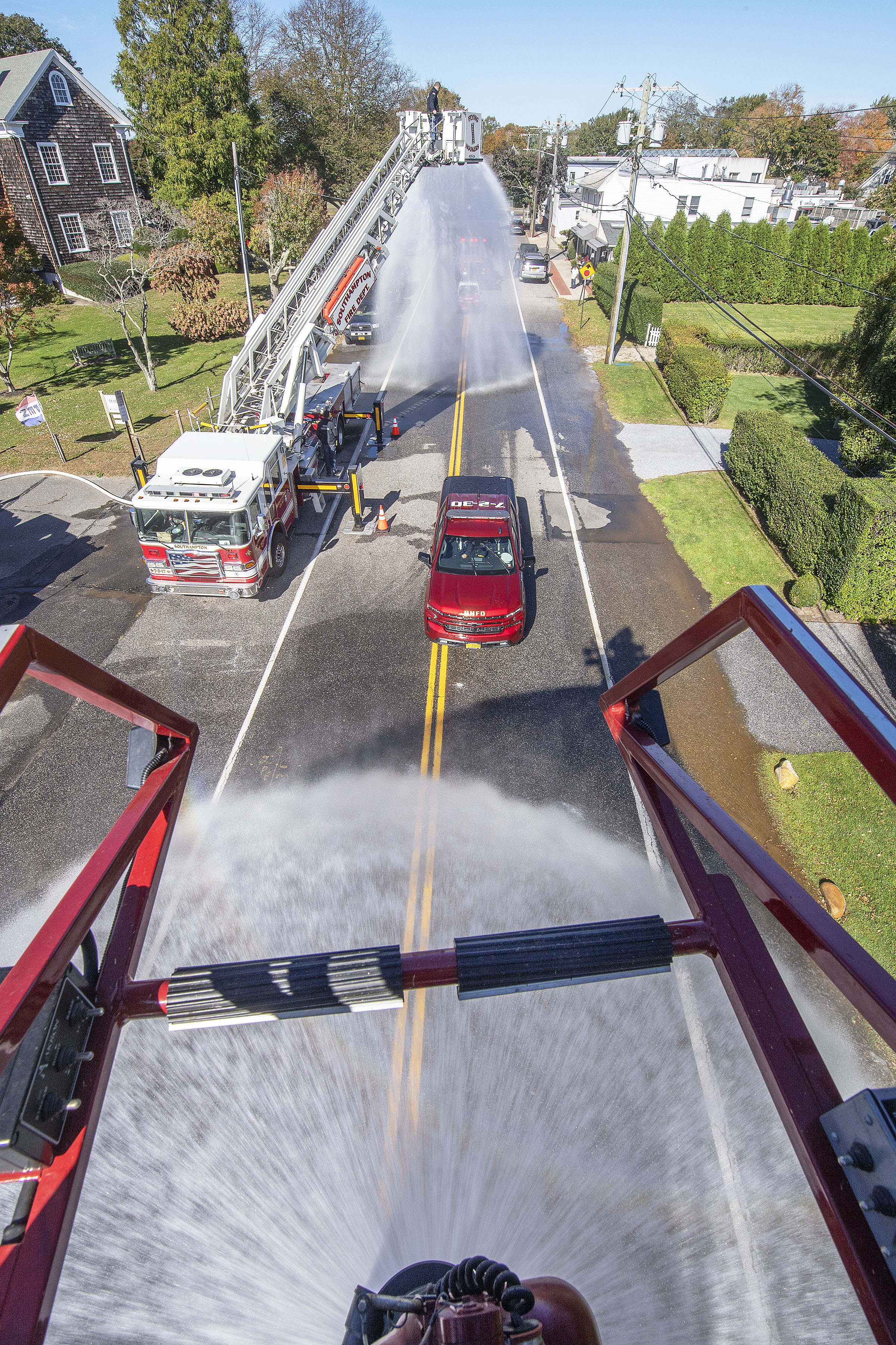 The new Bridgehampton Fire Department chief's truck passes under water deluges from the Southampton and Bridgehampton hook & ladder trucks as the Bridgehampton Fire Department hosted a Wetdown Ceremony for three new pieces of apparatus - a new Chief's pickup truck, a small, light-duty utility vehicle and a new brush truck - at their headquarters on School Street on Saturday.   MICHAEL HELLER