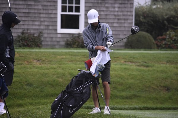 On a rainy day, Westhampton Beach senior Mackenzie Kim wipes off his driver before teeing off on hole one.