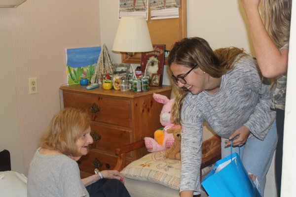 Allyson hands resident Helen Vermont a gift bag with a dog stuffed animal to add to her collection.