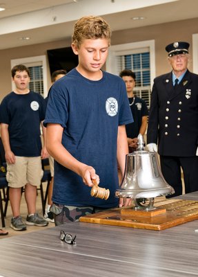 Michael Mignone, a member of the Westhampton Beach Fire Department Juniors, strikes the department’s bell as part of a ceremony known as Striking the Four Fives. This was part of a ceremony organized by the juniors in remembrance of the tragedy of 9-11. Courtesy Westhampton Beach Fire Department