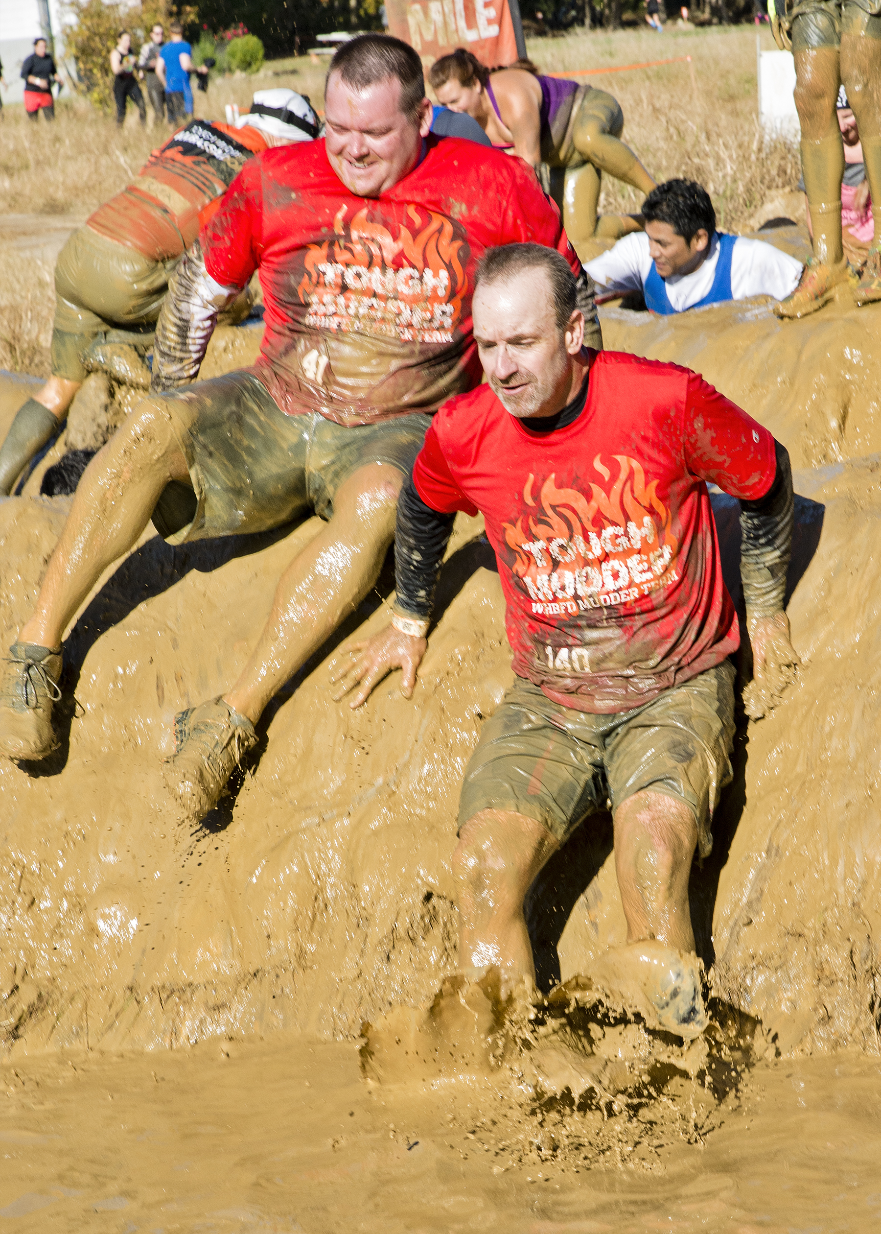 Westhampton Beach Fire Department                                                                                                                                                                                                                                                                 probationary firefighter Chris Winters, left, and Captain Dave Slover slide their way through the Mud Mile. Courtesy Westhampton Beach Fire Department