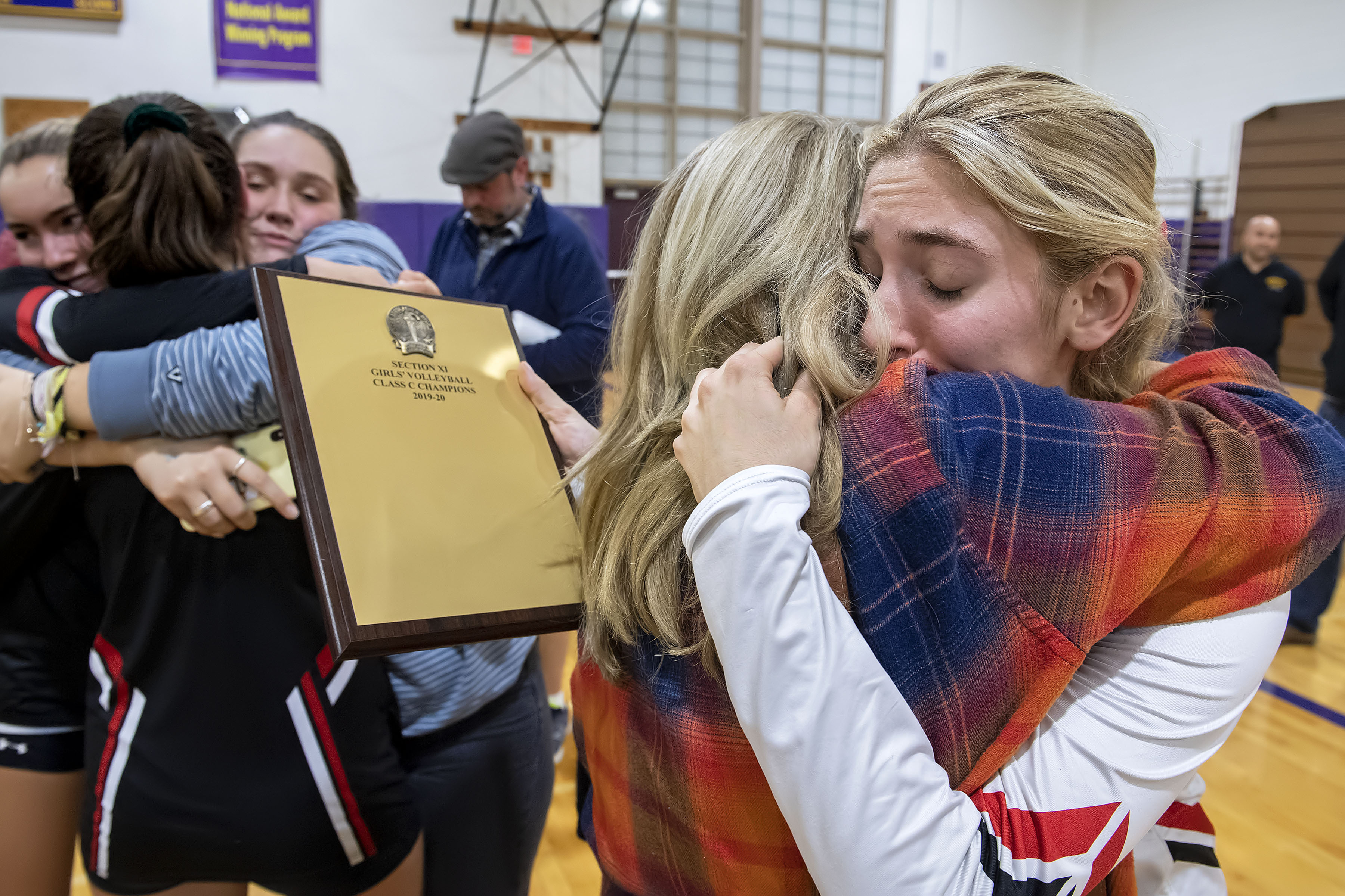 Lady Whalers head coach Donna Fischer gives a big hug to senior Samantha Cox as senior Olivia Cassone checks out the championship plaque.  MICHAEL HELLER
