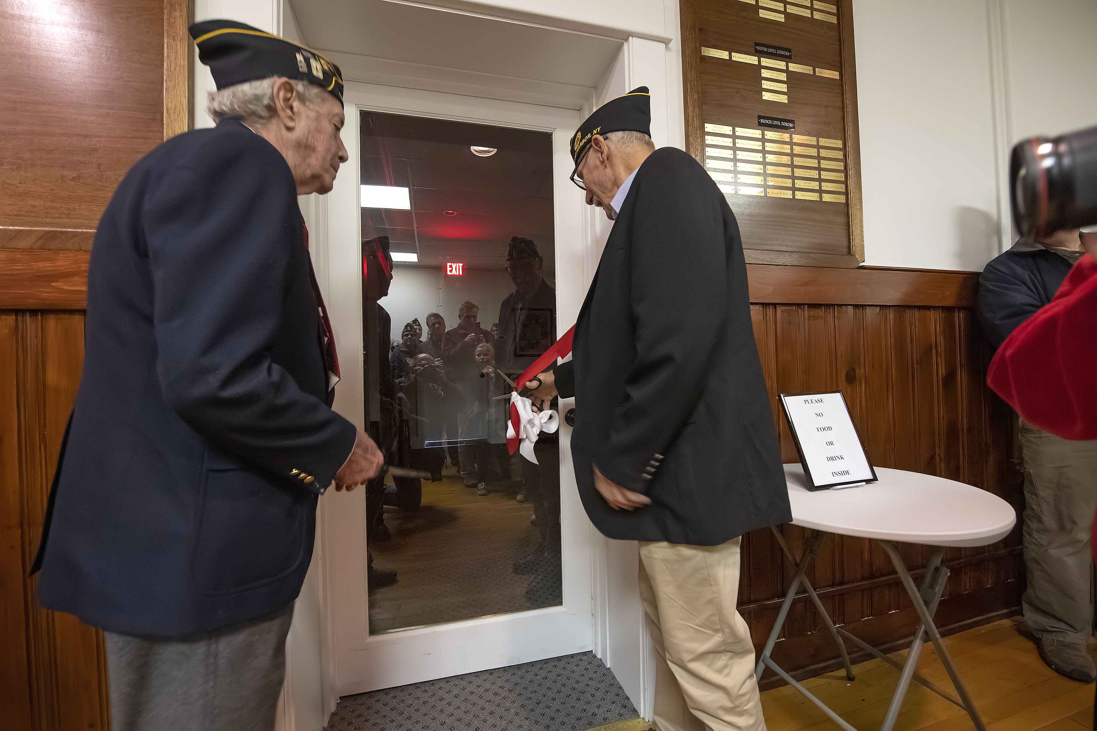 Sag Harbor veterans Chuck Lattanzio and Jim Laspesa cut the ribbon at the entrance of the new museum space at the American Legion Chelberg & Battle Post 388 following the 2019 Veterans Day Parade on Monday.   MICHAEL HELLER