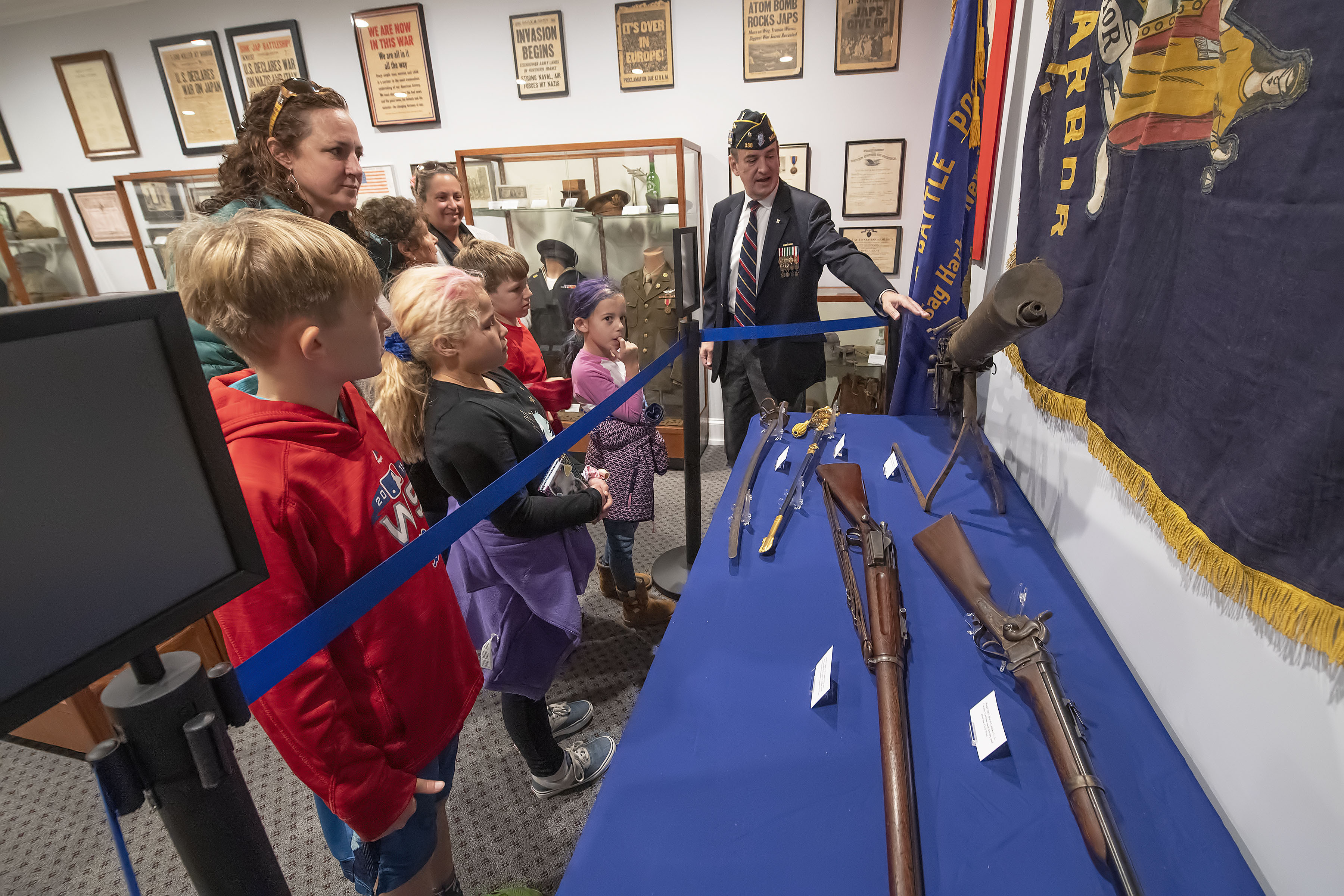 Legion Past Commander Paul Gerecke shows off some of the weapons on display during the grand opening of the new museum space at the American Legion Chelberg & Battle Post 388 following the 2019 Veterans Day Parade on Monday.    MICHAEL HELLER