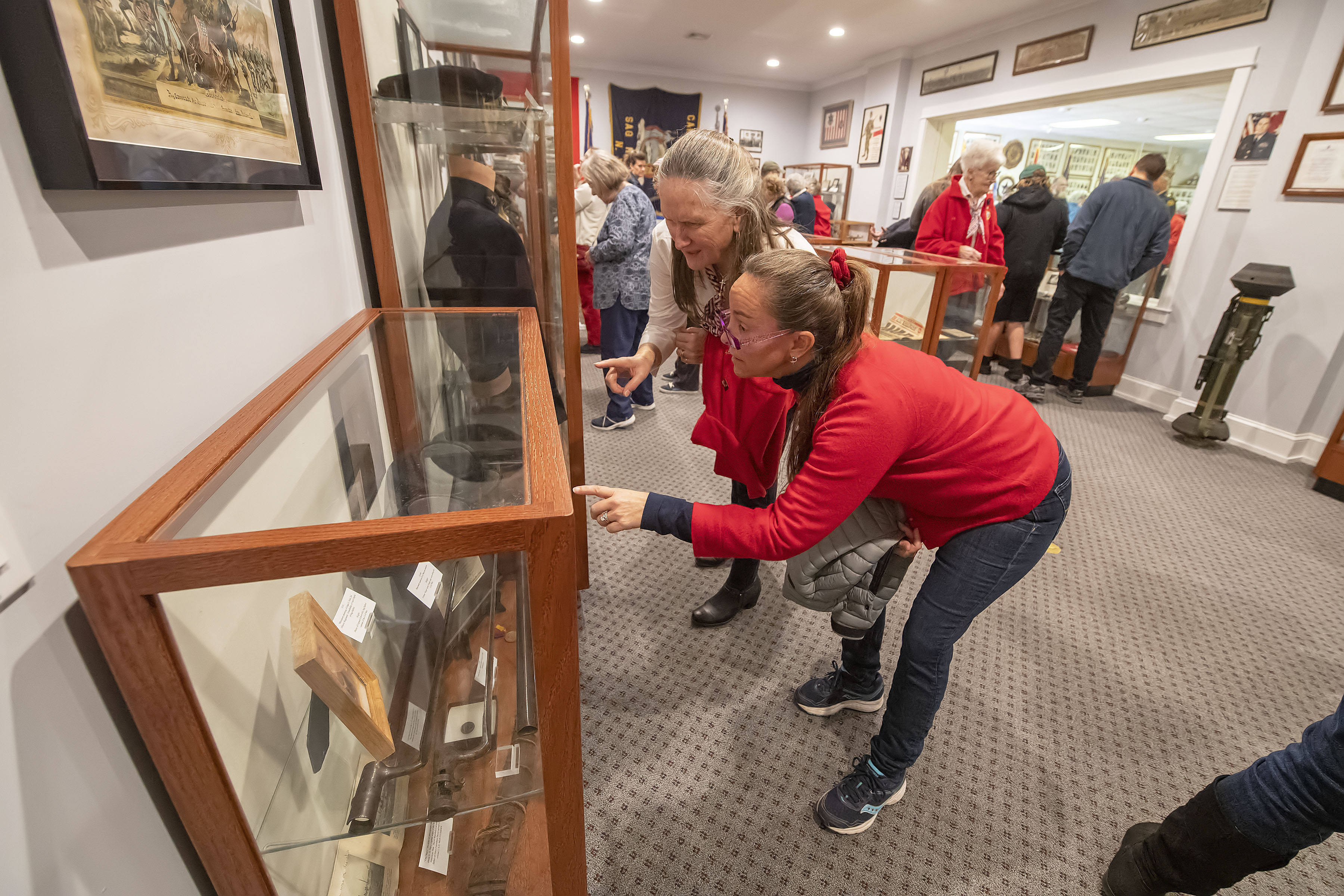 Rhodi Winchell and Stephanie Oddo check out some of the numerous artifacts on display during the grand opening of the new museum space at the American Legion Chelberg & Battle Post 388 following the 2019 Veterans Day Parade on Monday.  MICHAEL HELLER